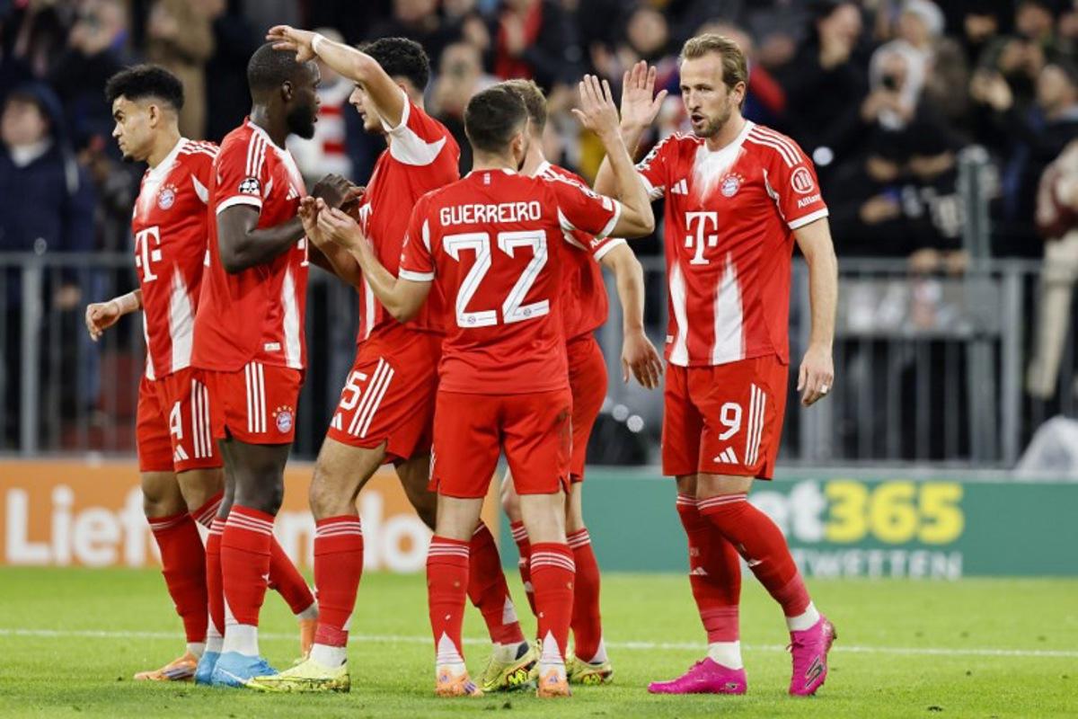 Bayern Munich's English forward #09 Harry Kane (R) celebrates scoring his team's second goal with Bayern Munich's Portuguese defender #22 Raphael Guerreiro and teammates during the UEFA Champions League football match between FC Bayern Munich and Club Brugge in Munich, southern Germany on October 22, 2025. Alexandra BEIER / AFP