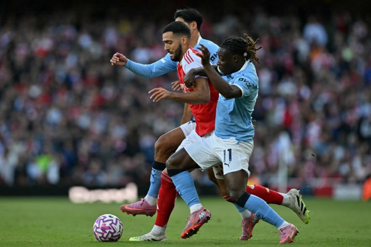 Arsenal's Spanish midfielder #23 Mikel Merino (C) vies with Manchester City's Dutch midfielder #04 Tijjani Reijnders (L) and Manchester City's Belgian midfielder #11 Jeremy Doku (R) during the English Premier League football match between Arsenal and Manchester City at the Emirates Stadium in London on September 21, 2025. Glyn KIRK / AFP