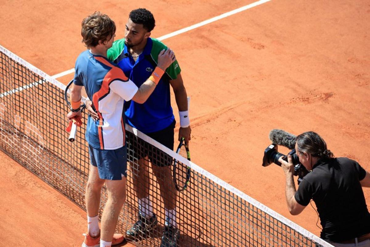 France's Arthur Fils (C) hugs Russia's Andrey Rublev (L) after winning during the Monte Carlo ATP Masters Series Tournament round of 16 tennis match on the Court des Princes at the Monte Carlo Country Club in Roquebrune-Cap-Martin on April 10, 2025. Valery HACHE / AFP