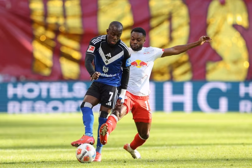 Hamburg's French-Ivorian forward #07 Jean-Luc Dompe (L) and Leipzig's German midfielder #17 Ridle Baku vie for the ball during the German first division Bundesliga football match RB Leipzig v Hamburg SV in Leipzig, eastern Germany on October 18, 2025. Ronny HARTMANN / AFP