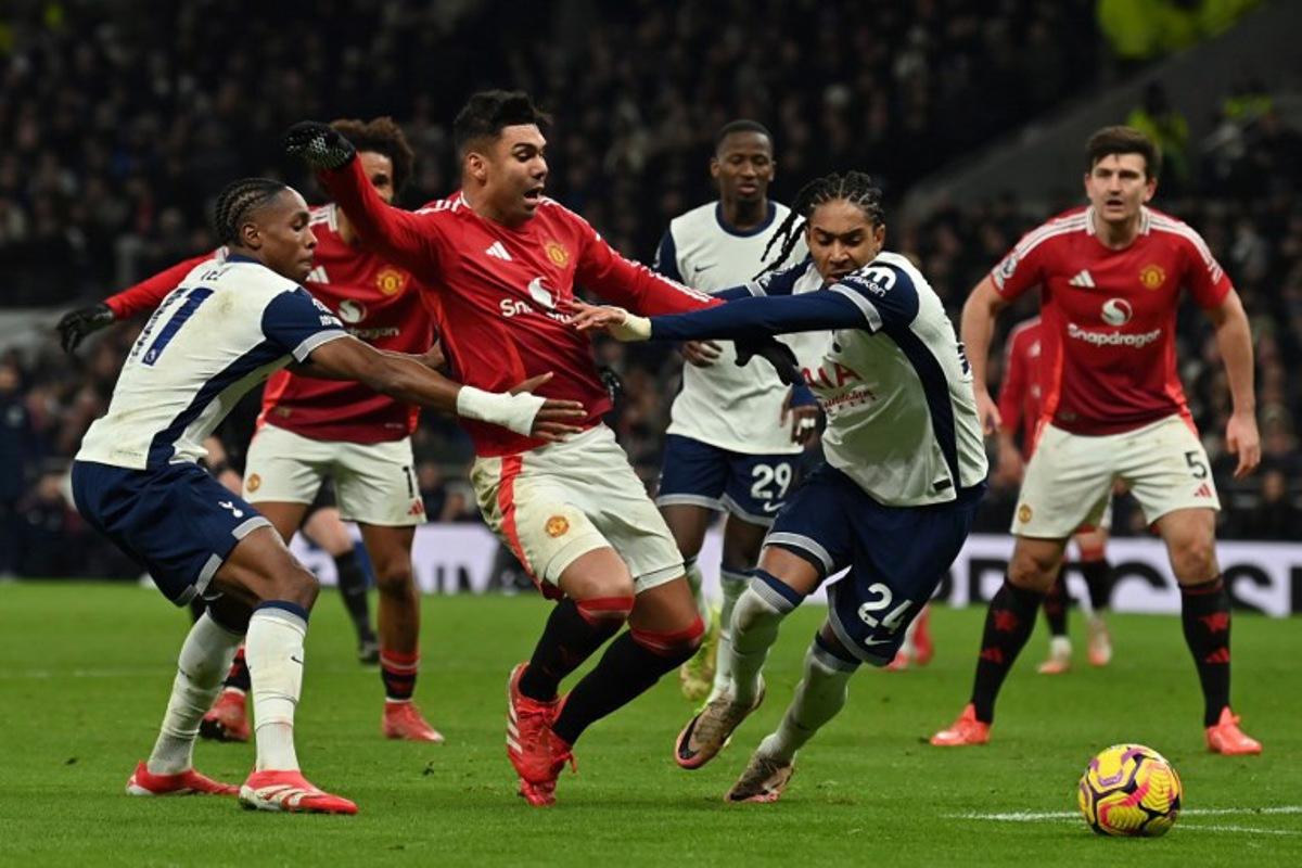 Manchester United's Brazilian midfielder #18 Casemiro (C) falls under a challenge from Tottenham Hotspur's French striker #11 Mathys Tel (L) and Tottenham Hotspur's English defender #24 Djed Spence (2R) but no penalty is given, during the English Premier League football match between Tottenham Hotspur and Manchester United at the Tottenham Hotspur Stadium in London, on February 16, 2025. Glyn KIRK / AFP