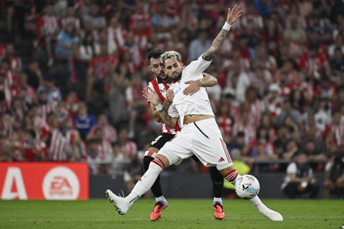 Athletic Bilbao's Spanish defender #04 Aitor Paredes (L) and Sevilla's Belgian forward #24 Adnan Januzaj fight for the ball during the Spanish league football match between Athletic Club Bilbao and Sevilla FC at San Mames Stadium in Bilbao on August 17, 2025. ANDER GILLENEA / AFP