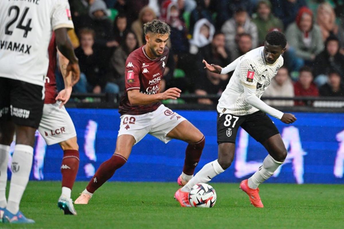Metz's Algerian defender #22 Kevin Van Den Kerkhof (L) fights for the ball with Reims' Malian midfielder #87 Ange Martial Tia during the French L1 - L2 playoff first leg football match between FC Metz and Stade de Reims at the Saint-Symphorien Stadium in Metz, northeastern France, on May 21, 2025. Jean-Christophe VERHAEGEN / AFP