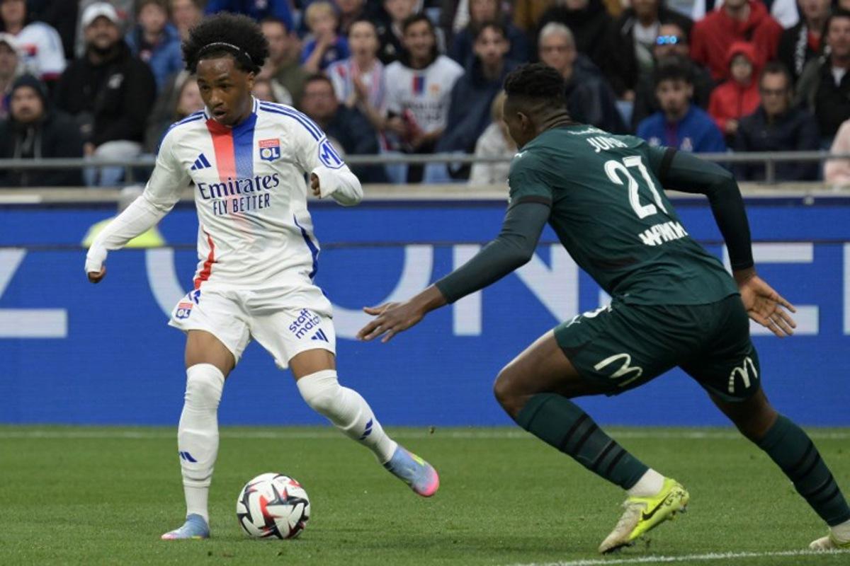 Lyon's Belgian forward #11 Malick Fofana (L) runs with the ball under pressure from Lens' Sierra Leonean defender #27 Juma Bah (R) during the French L1 football match between Olympique Lyonnais (OL) and RC Lens at Parc Olympique Lyonnais in Decines-Charpieu, central-eastern France, on May 4, 2025. JEAN-PHILIPPE KSIAZEK / AFP