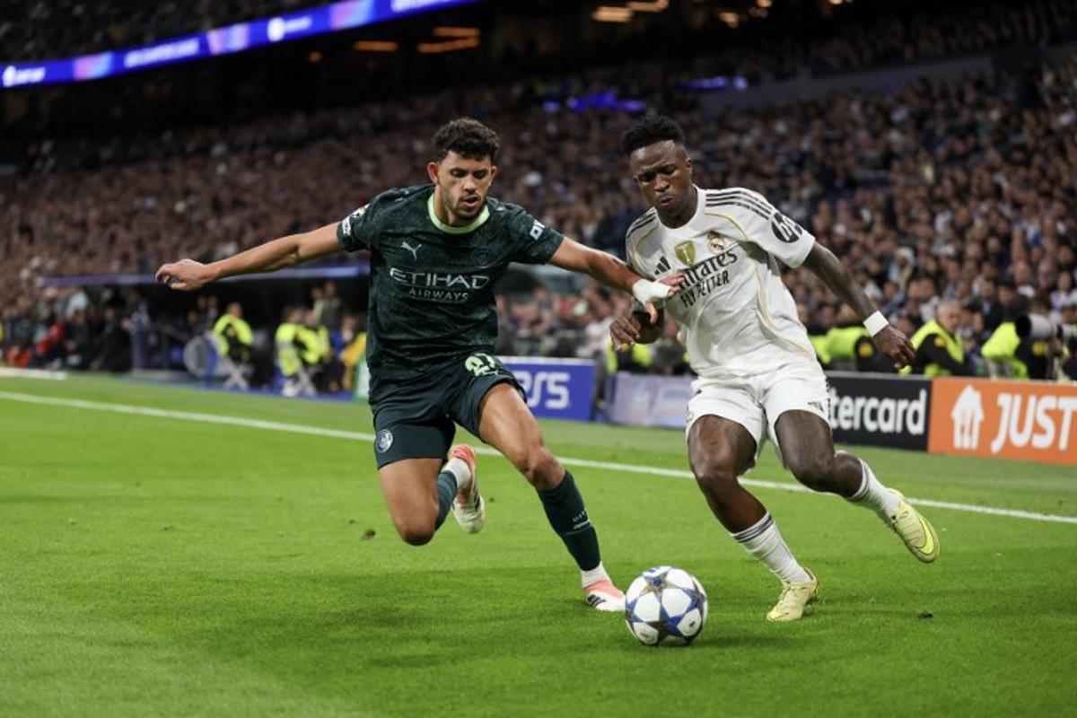 Manchester City's Portuguese midfielder #27 Matheus Nunes (L) vies for the ball with Real Madrid's Brazilian forward #07 Vinicius Junior during the UEFA Champions League league phase day 6 football match between Real Madrid CF and Manchester City at Santiago Bernabeu Stadium in Madrid on December 10, 2025. Thomas COEX / AFP