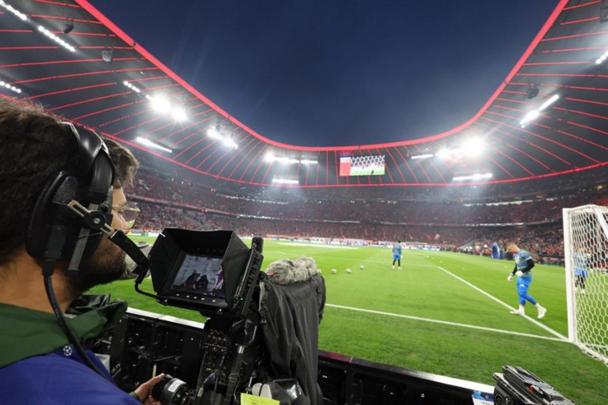 A cameraman looks at the screen of his camera from the sideline prior to the start of the UEFA Champions League quarter-final second leg football match between FC Bayern Munich and Real Madrid in Munich, southern Germany, on April 15, 2026. Karl-Josef HILDENBRAND / AFP