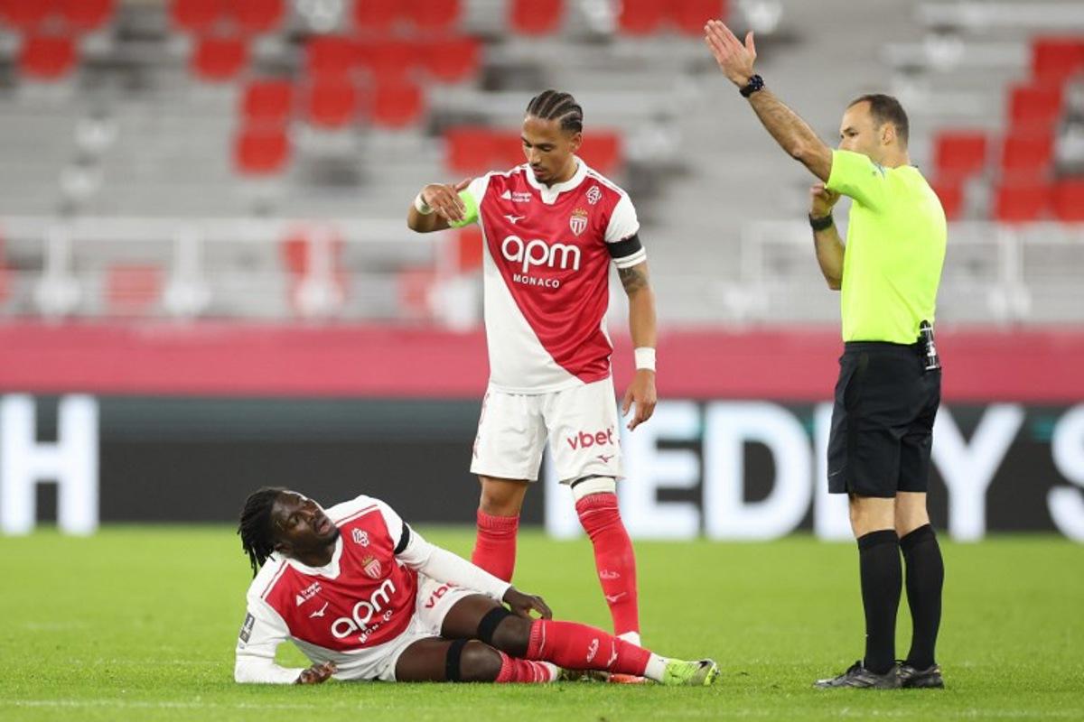 Monaco's Ghanaian defender #22 Mohammed Salisu (L) sustains an injury during the French L1 football match between AS Monaco and Olympique Lyonnais (OL) at the Stade Louis II in the Principality of Monaco on January 3, 2026. Valery HACHE / AFP