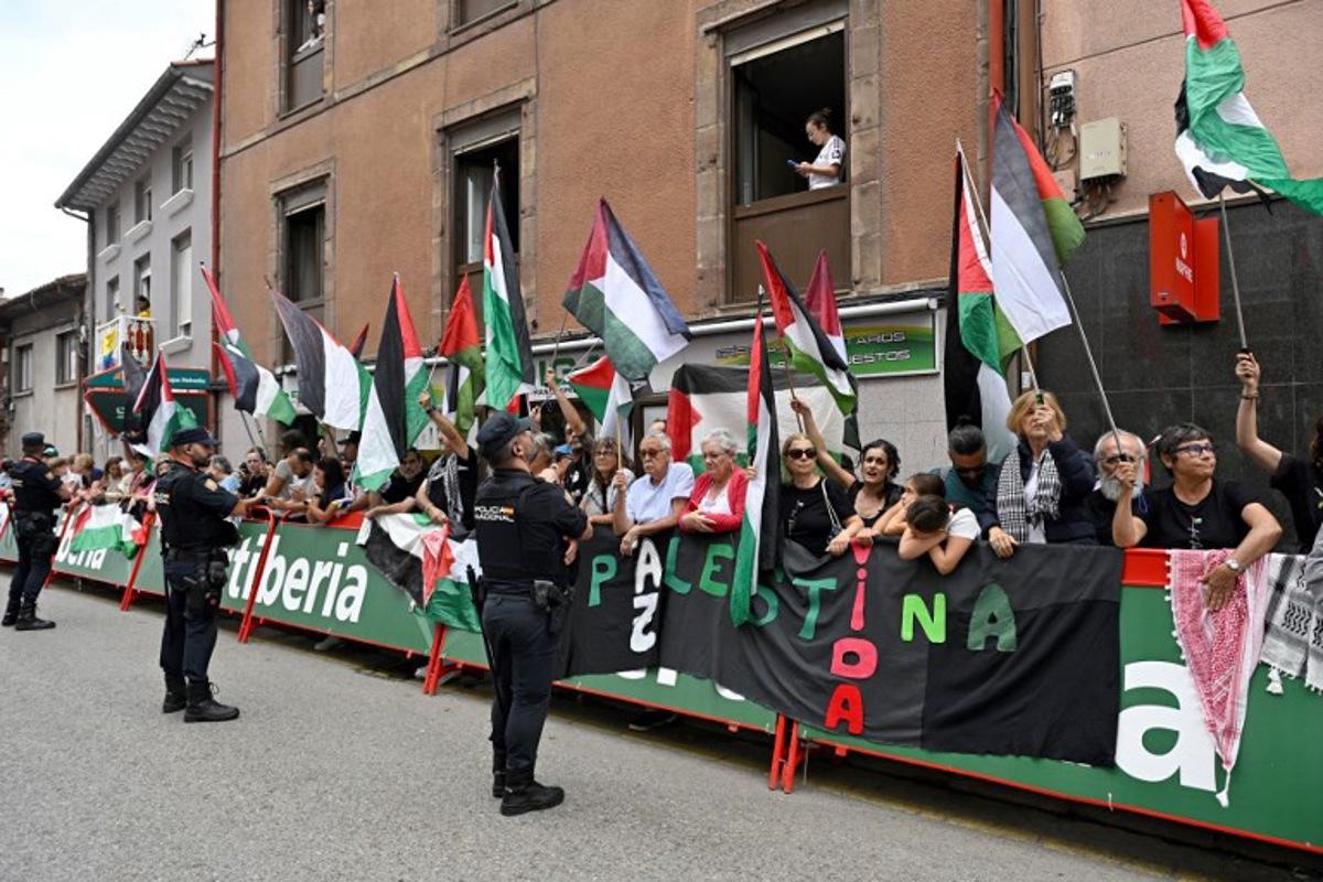 Police officers stand as Pro-Palestinian demonstrators wave Palestinian flags at the finish line of the 12th stage of the Vuelta a Espana, a 144,9 km race between Laredo and Corrales de Buelna, on September 4, 2025. ANDER GILLENEA / AFP