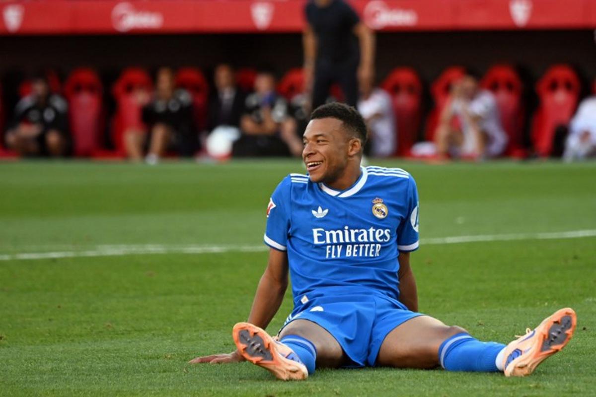 Real Madrid's French forward #10 Kylian Mbappe smiles as he sits on the pitch during the Spanish league football match between Sevilla FC and Real Madrid CF at the Sanchez Pizjuan stadium in Seville on May 17, 2026. CRISTINA QUICLER / AFP