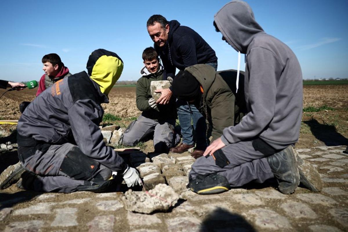 Workers repair cobblestones on the route of the Paris-Roubaix cycling race, in presence of race director Thierry Gouvenou (C), near Arenberg, on April 4, 2023, ahead of this week-end's women and men races. Anne-Christine POUJOULAT / AFP