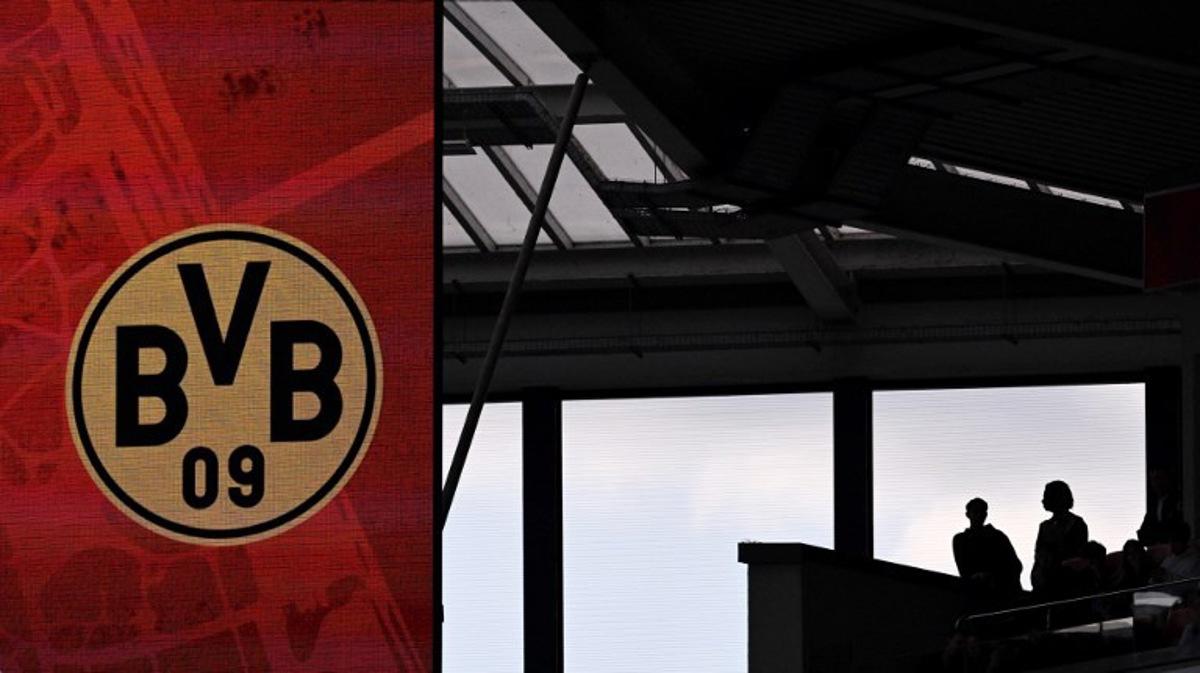 Football fans are seen on the stands next to a display with the BVB Borussia Dortmund logo during the German first division Bundesliga football match between 1 FSV Mainz 05 and Borussia Dortmund in Mainz, western Germany on September 27, 2025. Kirill KUDRYAVTSEV / AFP