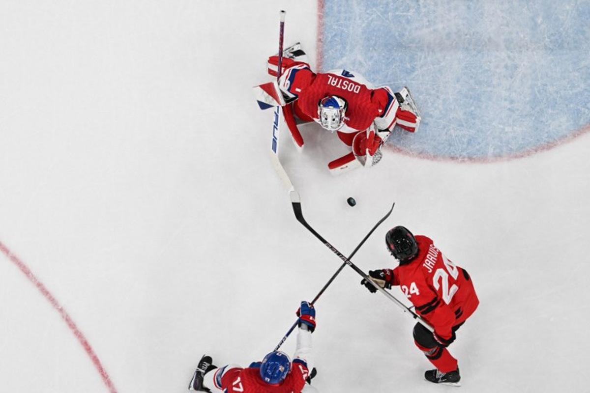 Czech Republic's #17 Filip Hronek (L) fights for the puck with Canada's #24 Seth Jarvis (R) in front of Czech Republic's goalkeeper #01 Lukas Dostal (C) during the men's play-off quarter-final ice hockey match between Canada and Czech Republic at the Milano Santagiulia Ice Hockey Arena during the Milano Cortina 2026 Winter Olympic Games in Milan, on February 18, 2026. Alexander NEMENOV / AFP