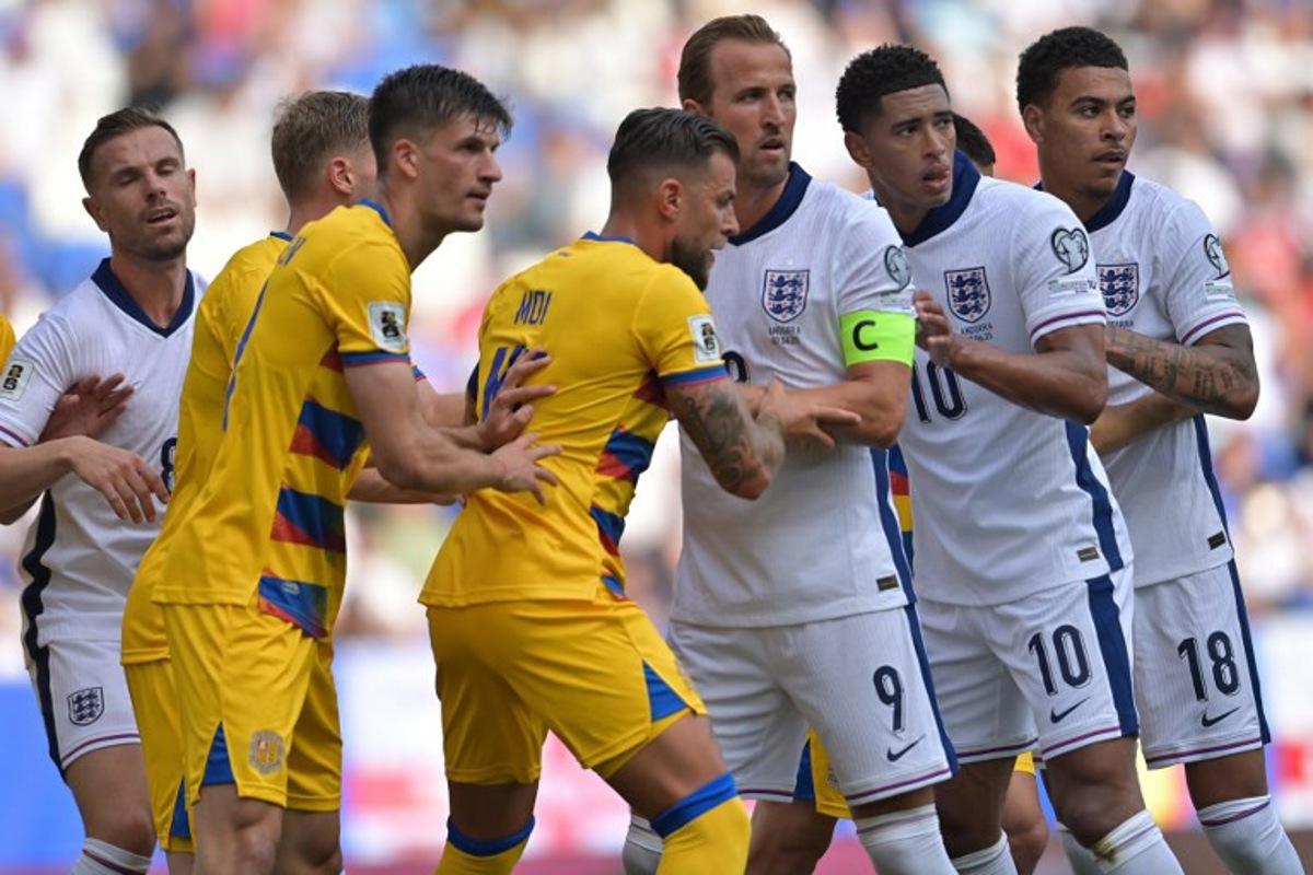 England forward #18 Morgan Rogers, England's midfielder #10 Jude Bellingham and England's forward #09 Harry Kane vie with Andorra's defender #15 Moises San Nicolas (C) and Andorra's midfielder #19 Joel Guillen Garcia (5R) during the 2026 World Cup qualifiers Europe zone, 1st round group K football match between Andorra and England at RCDE Stadium in Cornella de Llobregat, on June 7, 2025. MANAURE QUINTERO / AFP