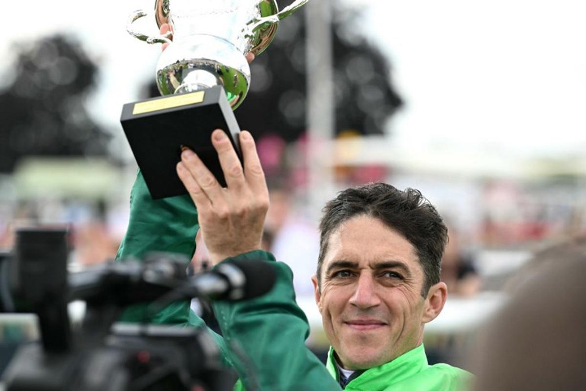 Belgium's Christophe Soumillon riding "Gezora" holds the trophy after winning the Diane Longines prize horse race at the Chantilly race course, north of Paris, on June 15, 2025. Hugo MATHY / AFP