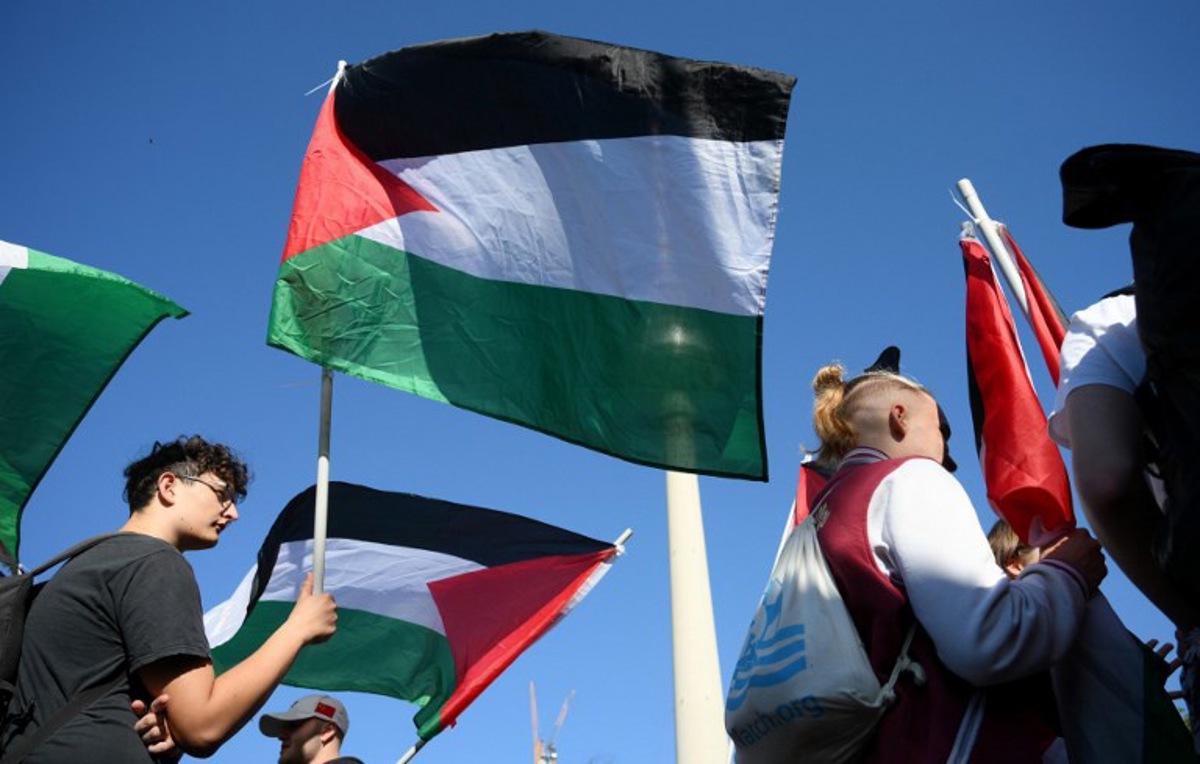 A participant displays a Palestinian flag during a demonstration under the motto 'Draw the red line with us: Together for Gaza!' in Berlin on September 27, 2025. RALF HIRSCHBERGER / AFP