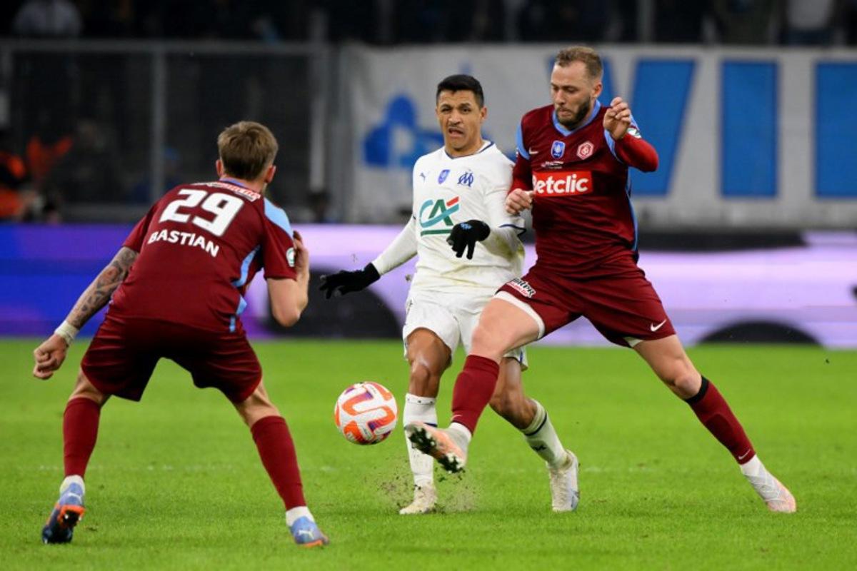 Marseille's Chilean forward Alexis Sanchez (C) fights for the ball with Annecy's French midfielder Maxime Bastian (L) during the French Cup quarter-final football match between Olympique de Marseille (OM) and Annecy at the Velodrome stadium in Marseille, southern France, on March 1, 2023. Nicolas TUCAT / AFP