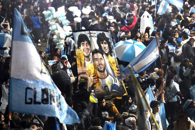 Fans hold a banner depicting Argentine football legends Diego Maradona, Mario Kempes and Lionel Messi holding FIFA World Cup trophies as supporters gather near the Argentine Football Association (AFA) training camp in Ezeiza, Buenos Aires Province, on July 20, 2026, while awaiting the arrival of Argentina's national football team from the United States following its defeat in the 2026 FIFA World Cup final. Luis ROBAYO / AFP