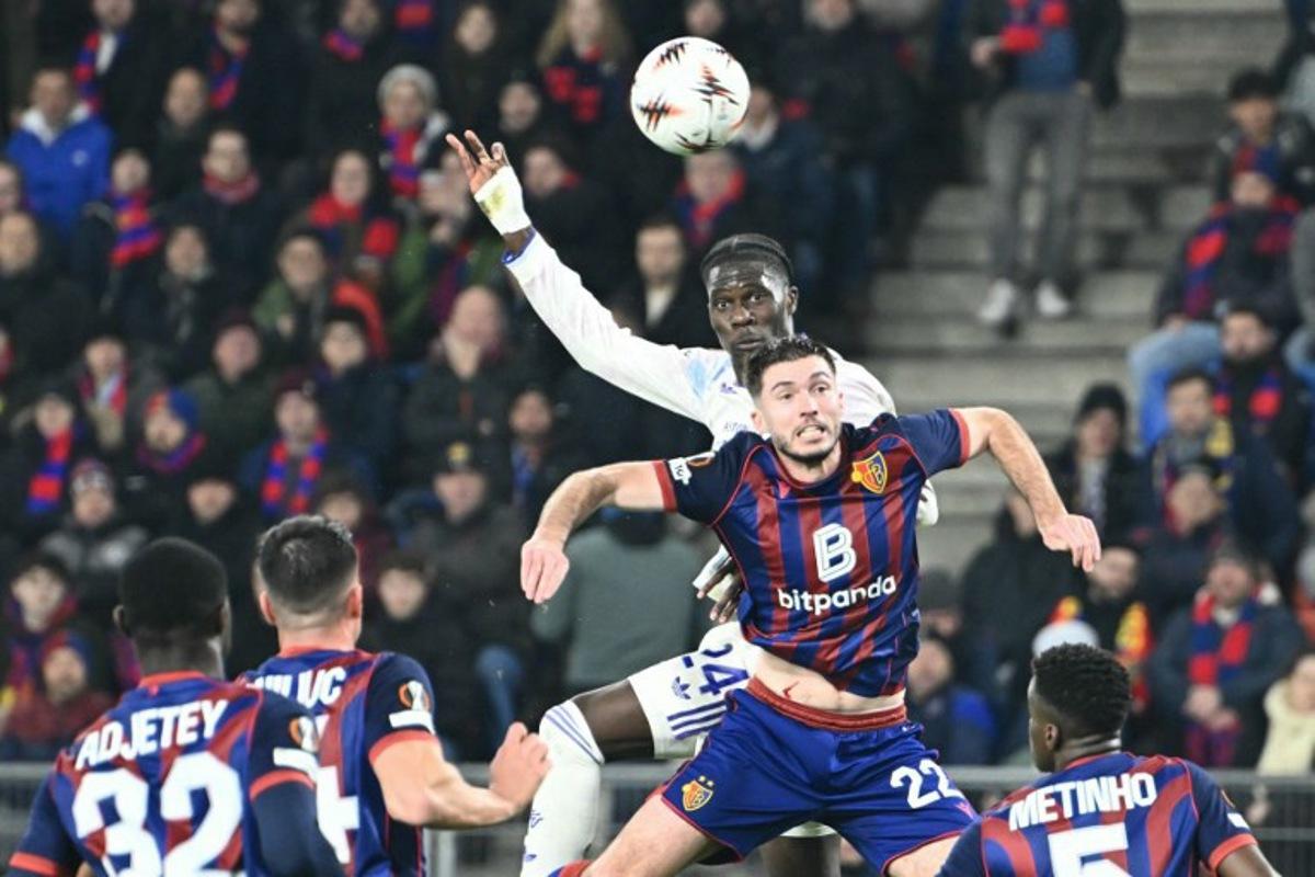 Aston Villa's Belgian midfielder #24 Amadou Onana (C) fights to head the ball with Basel's French midfielder #22 Leo Leroy (R) during the UEFA Europa League, league phase, football match between FC Basel and Aston Villa at the St Jakob-Park stadium, in Basel, on December 11, 2025. SEBASTIEN BOZON / AFP