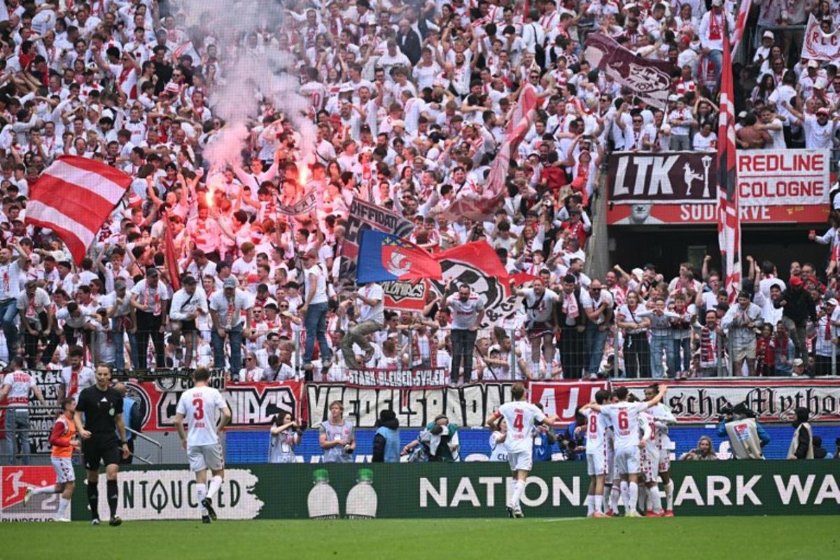 FC Cologne's German forward #09 Luca Waldschmidt (Hidden) celebrates with his team mates after scoring his team's second goal during the German second division Bundesliga football match between FC Cologne and FC Kaiserslautern in Cologne, western Germany on May 18, 2025. INA FASSBENDER / AFP