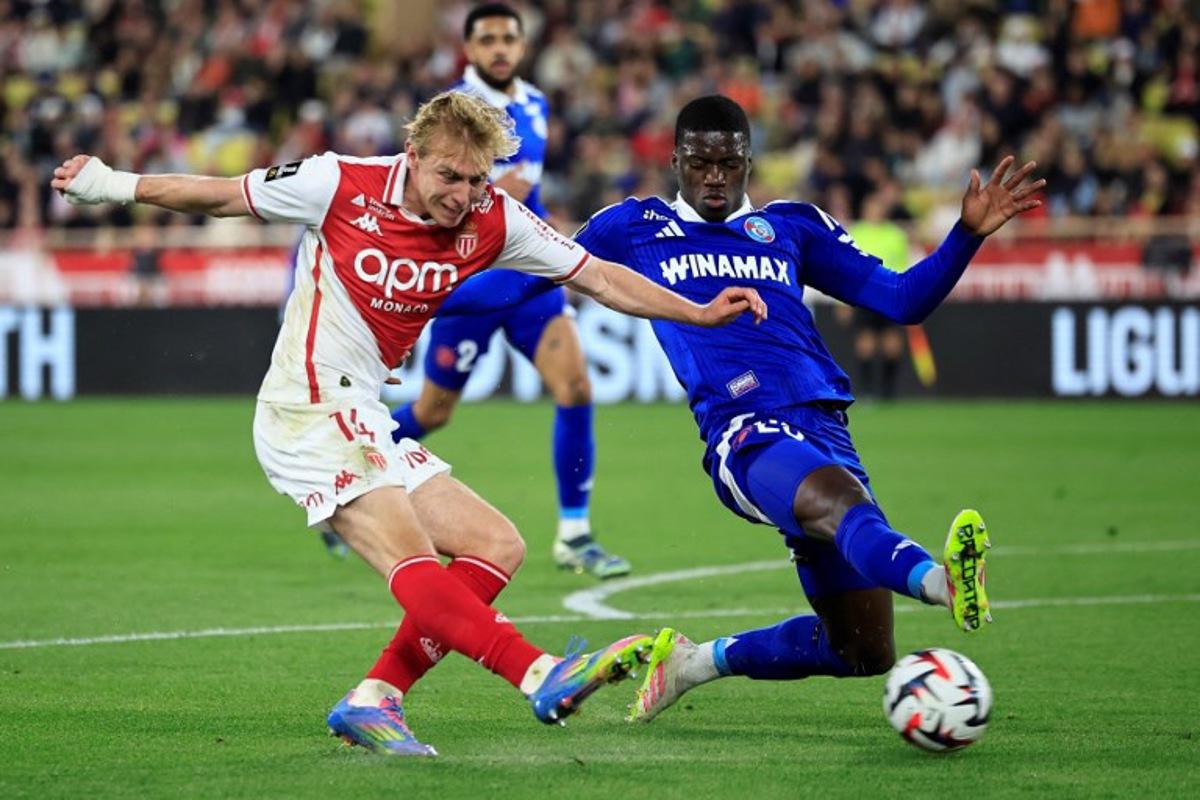 Monaco's Danish forward #14 Mika Biereth (L) shoots towards goal under pressure from Strasbourg's French defender #23 Mamadou Sarr (R) during the French L1 football match between AS Monaco and RC Strasbourg Alsace at the Louis II Stadium (Stade Louis II) in the Principality of Monaco on April 19, 2025. Valery HACHE / AFP
