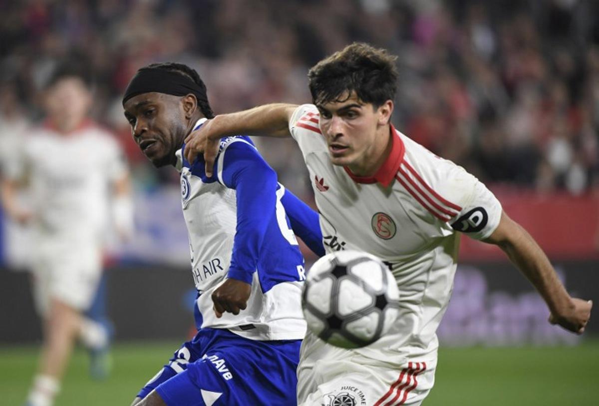 Atletico Madrid's English forward #22 Ademola Lookman fights for the ball with Sevilla's Spanish defender #16 Juanlu Sanchez during the Spanish league football match between Sevilla FC and Club Atletico de Madrid at the Ramon Sanchez Pizjuan stadium in Seville on April 11 , 2026. CRISTINA QUICLER / AFP