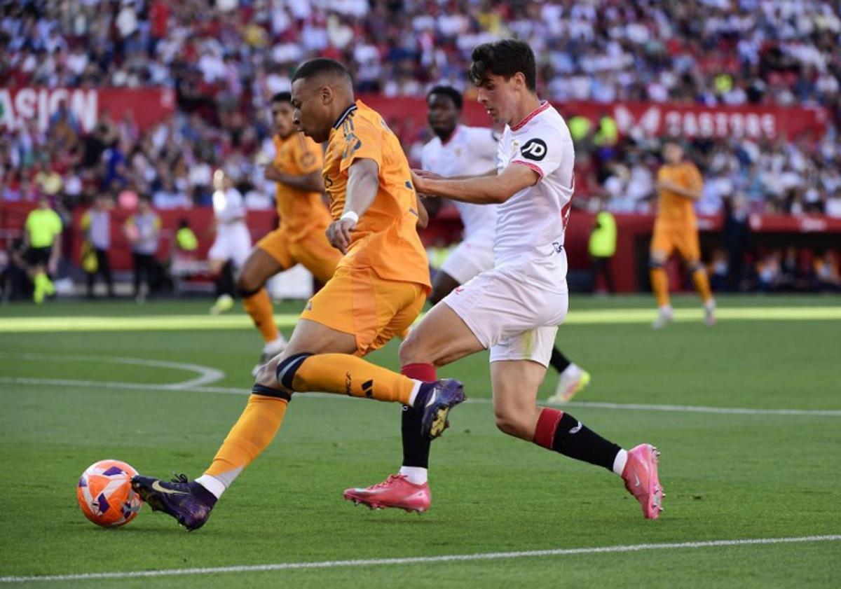 Real Madrid's French forward #09 Kylian Mbappe vies for the ball with Sevilla's Spanish defender #26 Juanlu Sanchez (R) during the Spanish league football match between Sevilla FC and Real Madrid CF at Ramon Sanchez Pizjuan Stadium in Seville on May 18, 2025. CRISTINA QUICLER / AFP