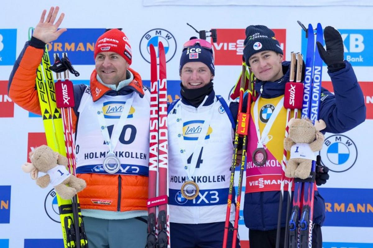 (From left) Second place Germany's Philipp Nawrath, winner Norway's Johan-Olav Botn and third place France's Eric Perrot celebrate on the podium after the men's 15km mass start event of the IBU Biathlon World Cup in Holmenkollen, Oslo on March 22, 2026. Heiko Junge / NTB / AFP