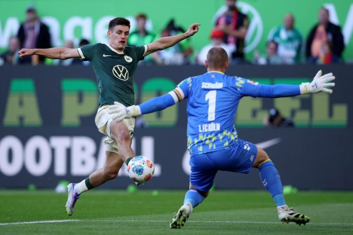 Wolfsburg's Danish defender #21 Joakim Maehle (L) and FC Cologne's German goalkeeper #01 Marvin Schwaebe vie for the ball during the German first division Bundesliga football match between VfL Wolfsburg and FC Cologne in Wolfsburg, northern Germany, on September 13, 2025. Ronny HARTMANN / AFP