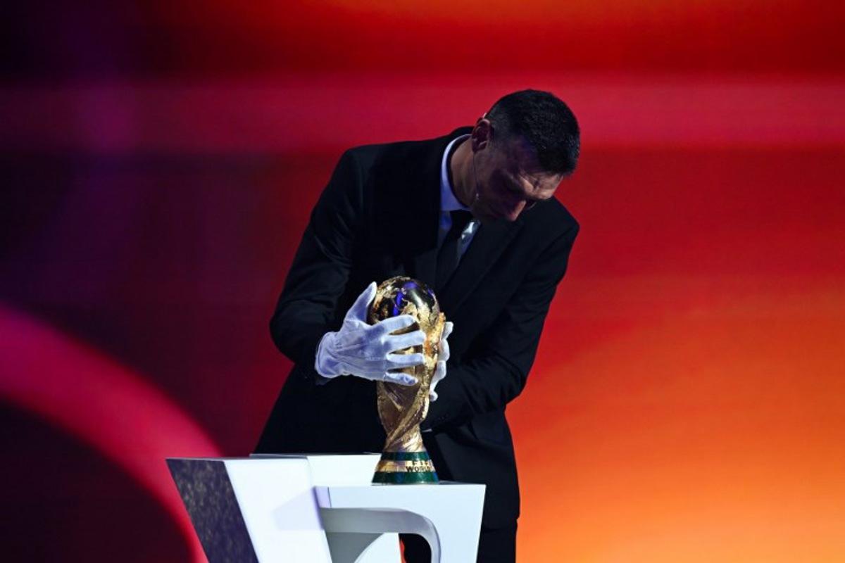 Argentina's head coach Lionel Scaloni places the FIFA World Cup trophy on stage during the draw for the 2026 FIFA Football World Cup taking place in the US, Canada and Mexico, at the Kennedy Center, in Washington, DC, on December 5, 2025. SAUL LOEB / AFP
