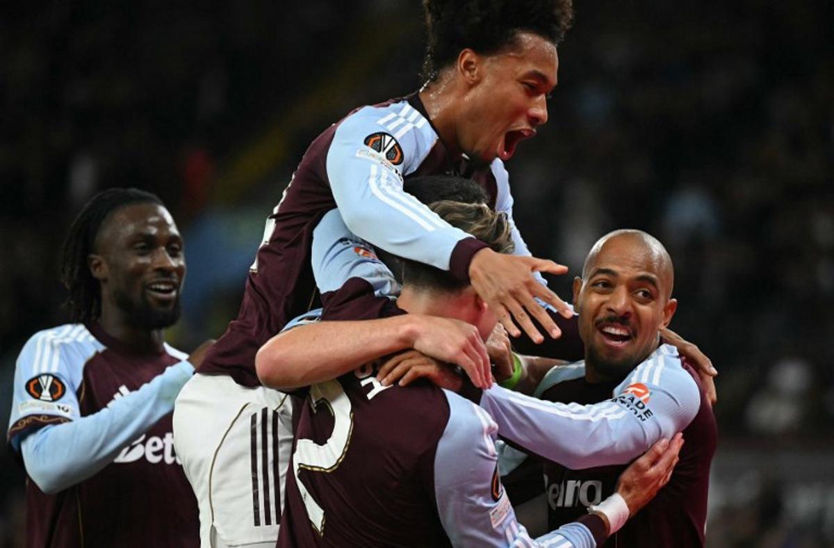Aston Villa's Scottish midfielder #07 John McGinn is mobbed by teammates after scoring the opening goal during the UEFA Europa League, league stage football match between Aston Villa and Bologna at Villa Park in Birmingham, central England on September 25, 2025. JUSTIN TALLIS / AFP