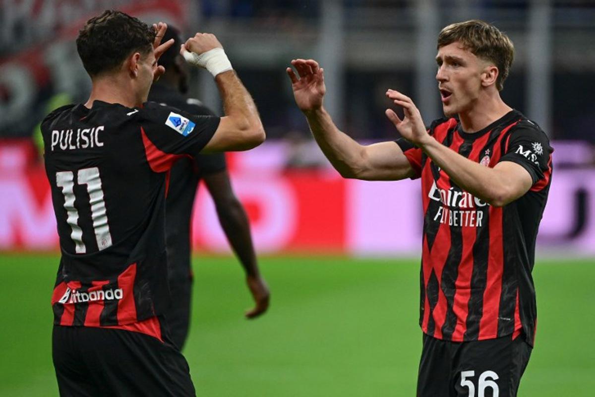 AC Milan's Begian midfielder #56 Alexis Saelemaekers (R) celebrates with his teammate AC Milan's US forward #11 Christian Pulisic after scoring his team's opening goal during the Italian Serie A football match between AC Milan and SSC Napoli at San Siro stadium in Milan, northern Italy, on September 28, 2025. Piero CRUCIATTI / AFP