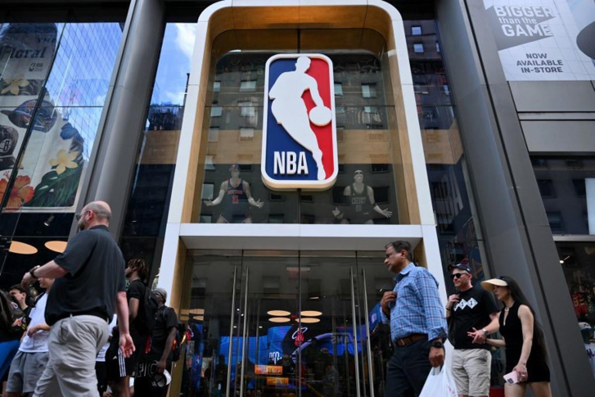 People walk past an NBA fan store with the NBA logo in New York on July 8, 2024. ANGELA WEISS / AFP