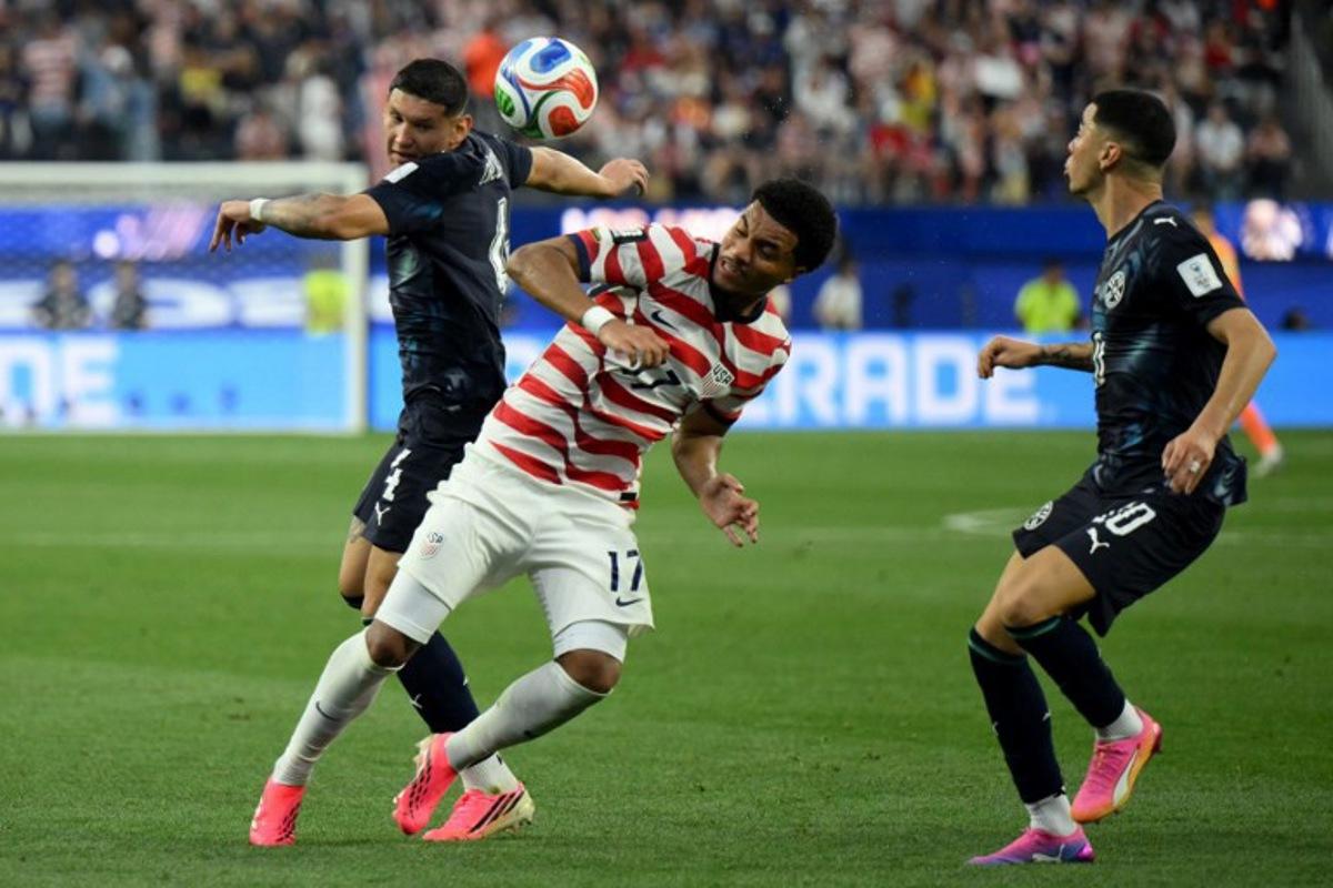 Paraguay's defender #04 Juan Jose Caceres (L) and US midfielder #17 Malik Tillman (C) fight for the ball during the 2026 World Cup Group D football match between USA and Paraguay at the Los Angeles Stadium in Inglewood on June 12, 2026. Patrick T. Fallon / AFP