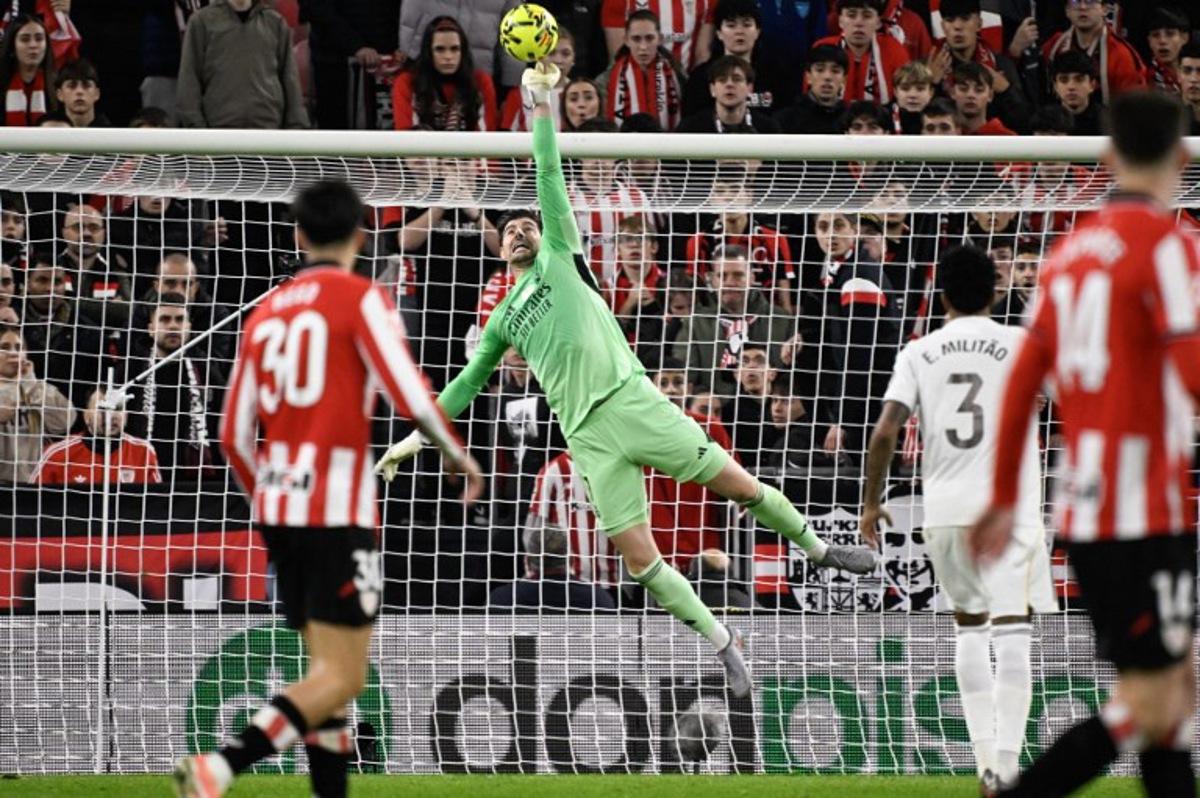 Real Madrid's Belgian goalkeeper #01 Thibaut Courtois leaps for the ball to make a save during the Spanish league football match between Athletic Club Bilbao and Real Madrid CF at the San Mames stadium in Bilbao on December 3, 2025. ANDER GILLENEA / AFP