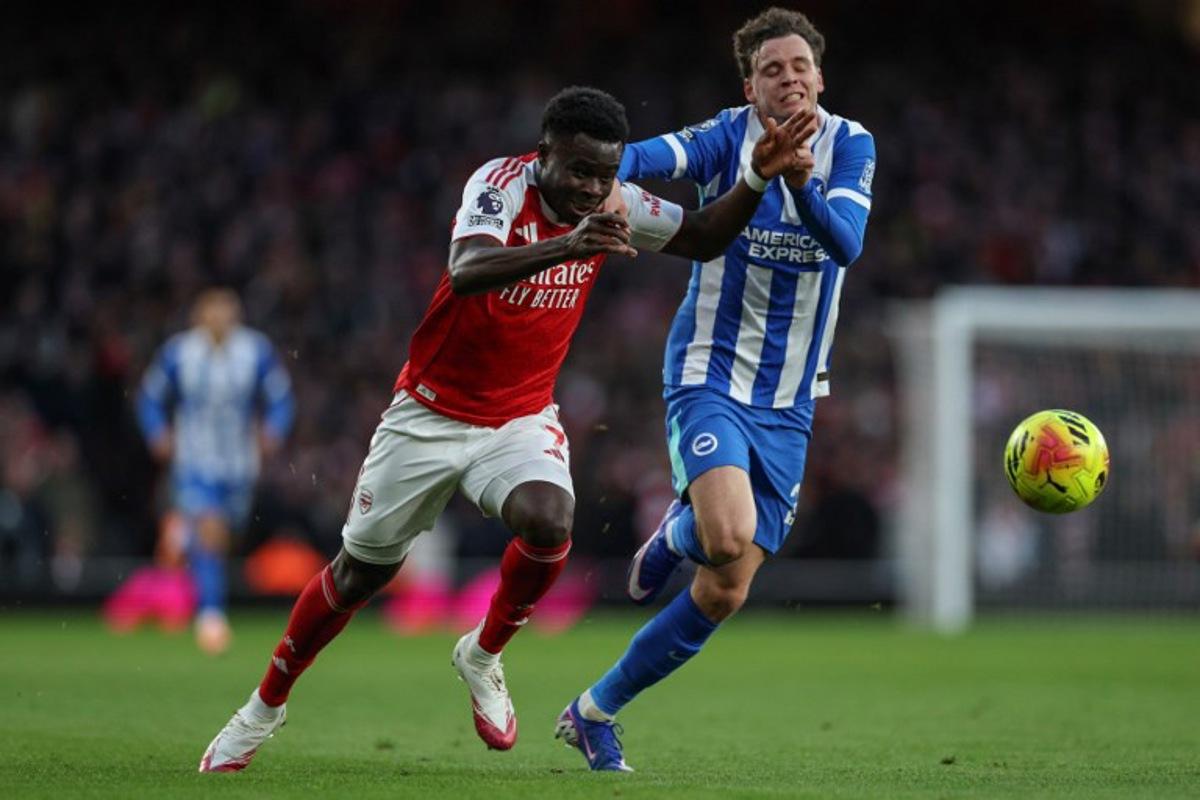 Arsenal's English midfielder #07 Bukayo Saka (L) is challenged by Brighton's Belgian defender #29 Maxim De Cuyper (R) during the English Premier League football match between Arsenal and Brighton and Hove Albion at the Emirates Stadium in London on December 27, 2025. Adrian Dennis / AFP