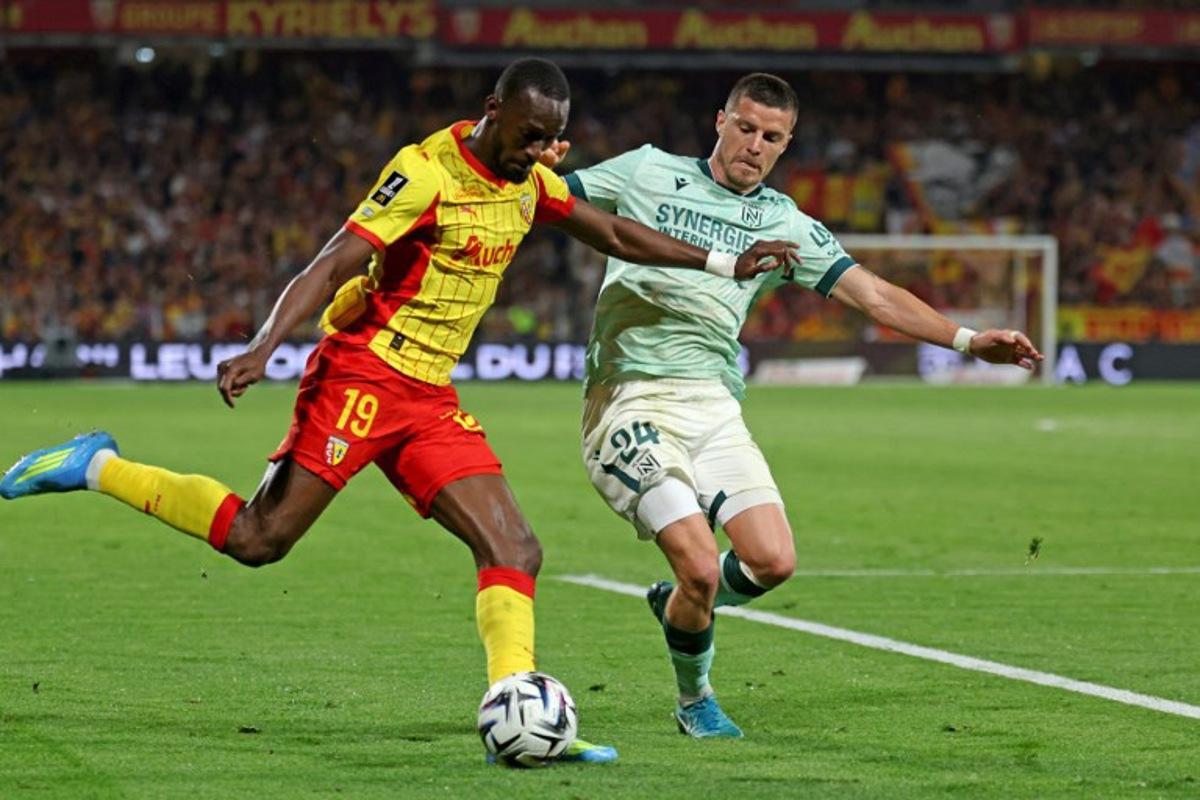 Lens' Senegalese forward #19 Abdallah Sima (L) and Nantes' French defender #24 Frederic Guilbert fight for the ball during the French L1 football match between RC Lens and FC Nantes at the Stade Bollaert-Delelis stadium in Lens on May 8, 2026. Francois LO PRESTI / AFP