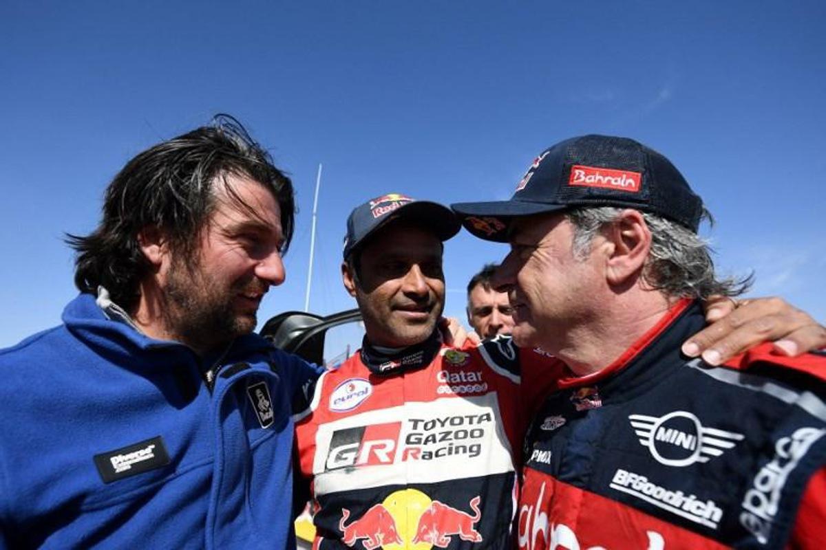 First-placed for the auto category JCW X-RAID Mini Team Spain's driver Carlos Sainz (R), celebrates as he is congratulated by second-placed Toyota's team Qatar's driver Nasser Al-Attiyah (C) and by diector of the Dakar 2020 David Castera (L) on the finish area in Qiddiya at the end of the stage 12 of the Dakar 2020 between Haradh and Qiddiya, Saudi Arabia, on January 17, 2020. FRANCK FIFE / AFP