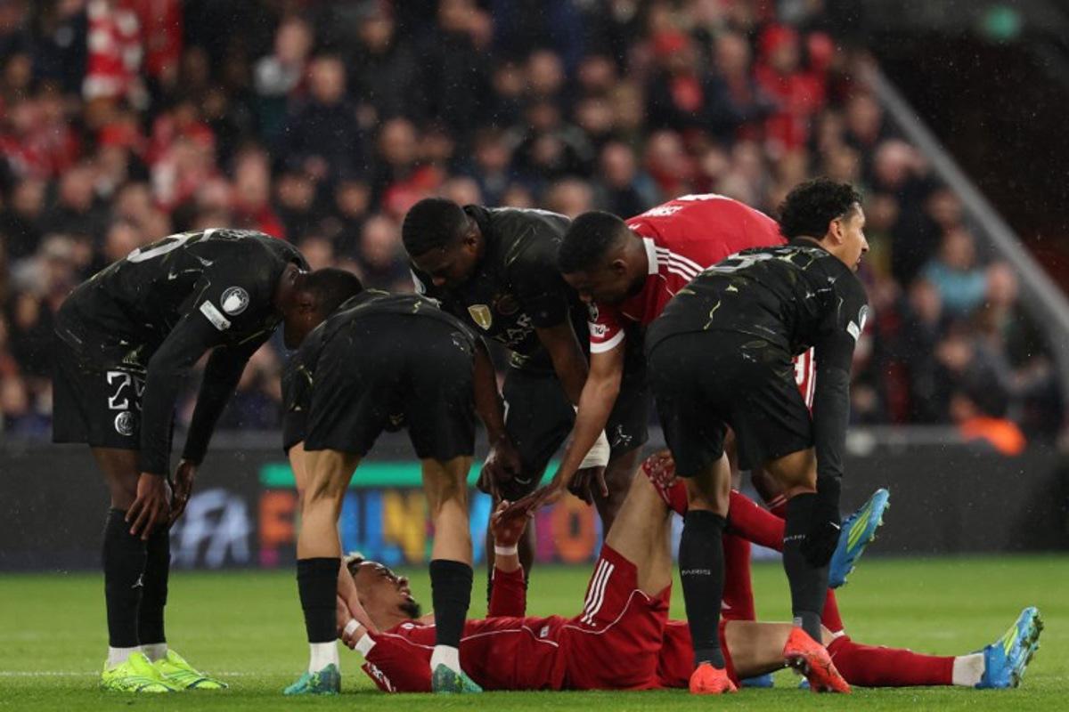 Players care for Liverpool's French striker #22 Hugo Ekitike who lies injured during the UEFA Champions League quarter final, second-leg football match between Liverpool and Paris Saint-Germain at Anfield in Liverpool, north west England on April 14, 2026. FRANCK FIFE / AFP