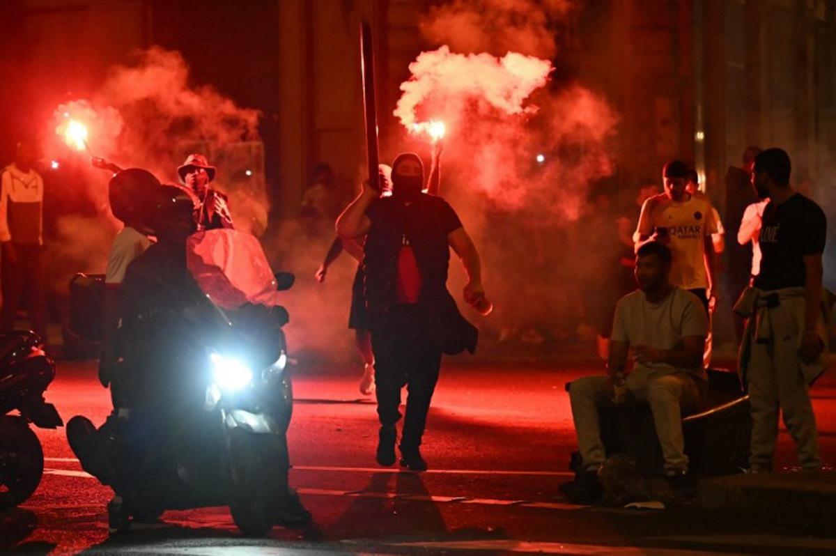 Paris Saint-Germain (PSG) supporters gather holding flares on a street in Paris early June 1, 2025, during celebrations following their 5-0 victory in the UEFA Champions League final football match between Paris Saint-Germain (PSG) and Inter Milan held in Munich. LOU BENOIST / AFP