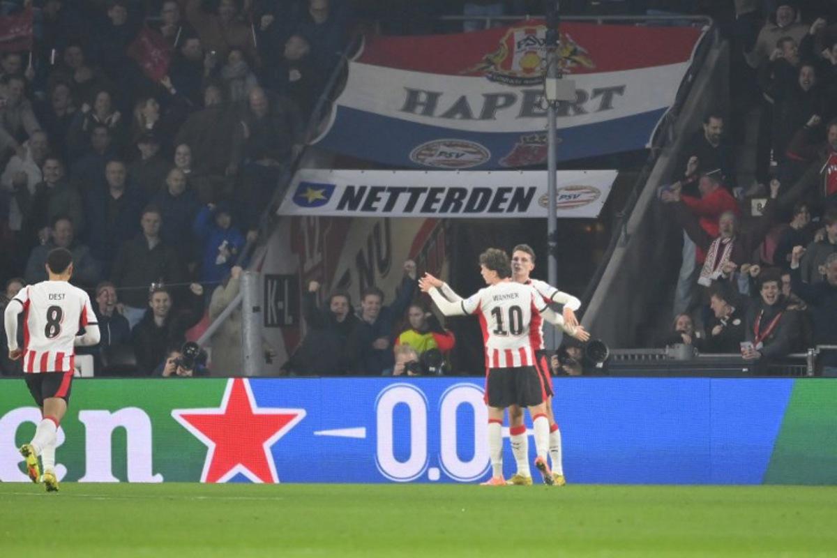 PSV Eindhoven's Dutch midfielder #20 Guus Til (R) celebrates scoring his team's first goal with teammates during the UEFA Champions League, league phase day 6, football match between PSV Eindhoven (NED) and Atletico Madrid (ESP), at the Philips Stadion, in Eindhoven, south of The Netherlands, on December 9, 2025. JOHN THYS / AFP