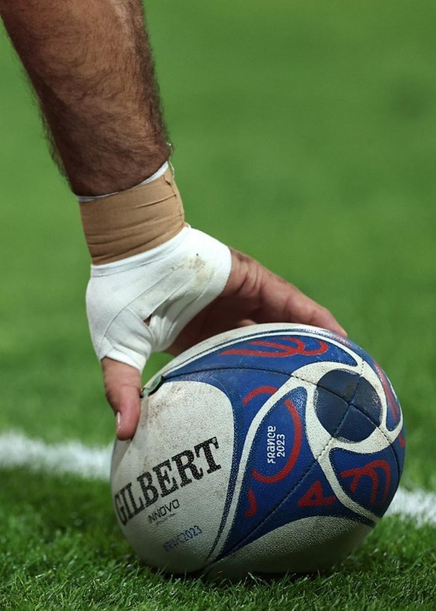 A players picks up a rugby ball ahead of the France 2023 Rugby World Cup Pool B match between Scotland and Romania at Pierre-Mauroy stadium in Villeneuve-d'Ascq near Lille, northern France, on September 30, 2023. FRANCK FIFE / AFP